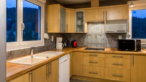 Una cocina moderna con armarios de madera, horno integrado, microondas y cafetera.