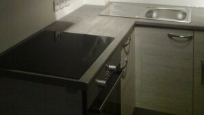 A compact kitchen with a stove, oven, and a single sink. - A country cottage "Ti Gwen" (Plonévez-Du-Faou)