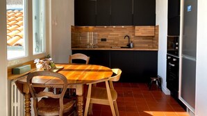 Una cocina compacta con una mesa de comedor de madera, sillas y un refrigerador negro.