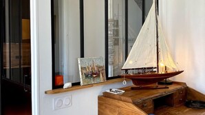 Una habitación con un escritorio de madera, una maqueta de un pequeño velero y un cuadro en la pared.