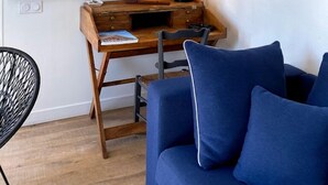 Una habitación con un escritorio de madera, un modelo de velero, un sofá azul y una silla negra.
