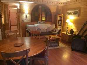 L’intérieur d’un chalet chaleureux, avec une table à manger en bois, un canapé et une bibliothèque.
