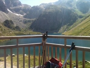Une terrasse en bois donnant sur un lac, avec des montagnes en arrière-plan.