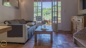 Ein Wohnzimmer mit einer Couch, einem Couchtisch mit Blumen, einem Fernseher und einem Holzschrank.