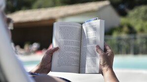 A person holding an open book with visible text, outdoors near a pool. - Mazet for 4 people. Les Garrigues Apt building of the valley of Baux Paradou (Paradou)