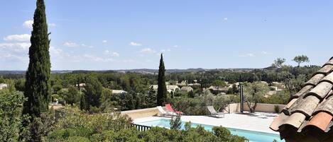 A pool with a clear view of the surrounding landscape, including trees and distant hills.