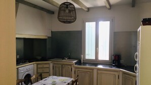 Una cocina con una mesa de comedor, una lavadora y un lámpara colgante.
