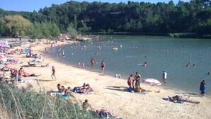Una playa con gente tomando el sol y nadando.