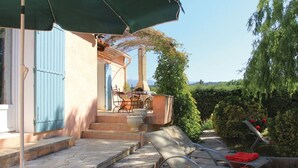 Un patio con suelo de piedra, mobiliario exterior y una mesa con sillas.