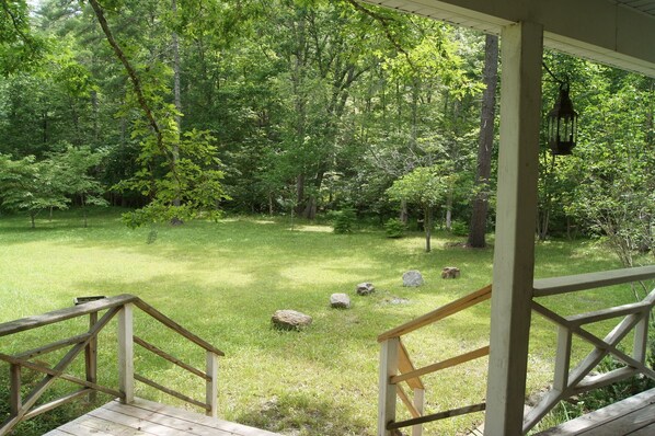 Une terrasse en bois dotée d’une rambarde, qui donne sur une zone herbeuse parsemée d’arbres.