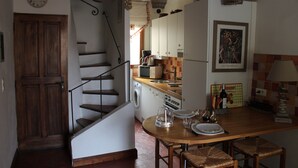 A kitchen with a wooden staircase, a washing machine, and a dining area with a table and chairs.