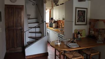 Une cuisine avec un escalier en bois, un lave-linge et un coin repas comprenant une table et des chaises.