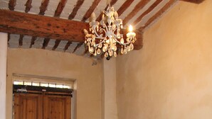 A room with a wooden door, a white pedestal fountain, and a chandelier.