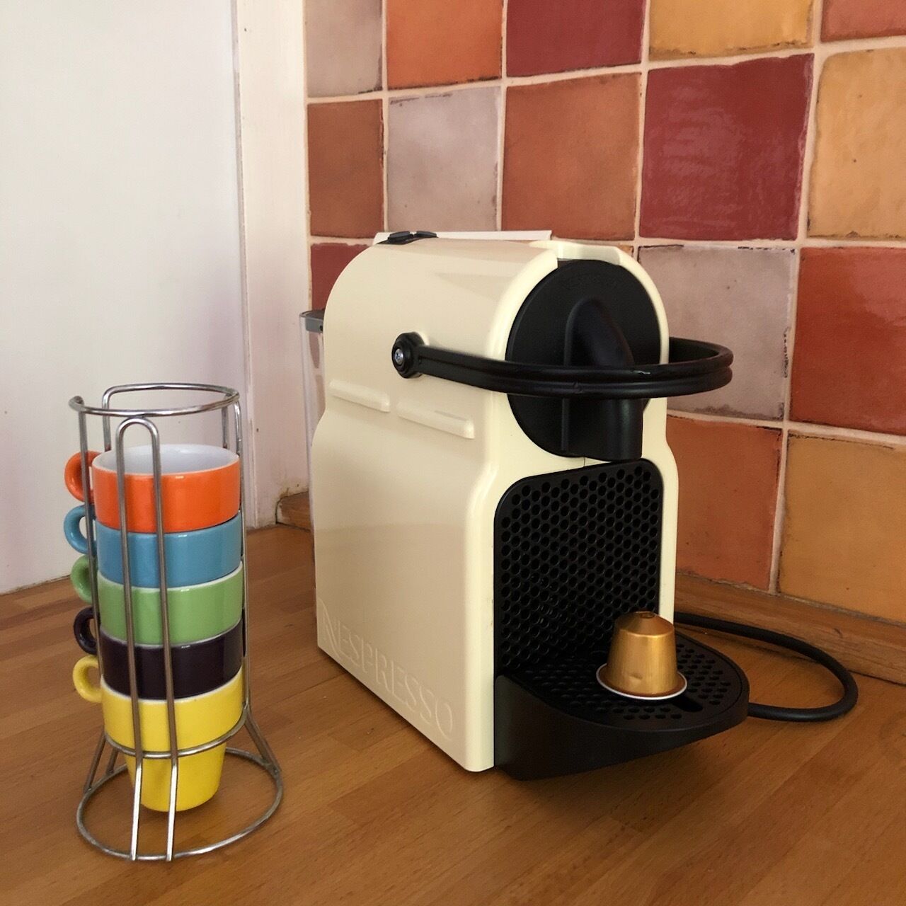 Une machine à café dotée d’un porte-tasse en métal contenant des tasses aux couleurs vives.