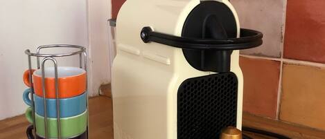 Une machine à café dotée d’un porte-tasse en métal contenant des tasses aux couleurs vives.