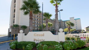 A hotel entrance with a sign reading "Grand Pointe," surrounded by palm trees and a landscaped garden. - GRAND POINTE 211....LOVELY CONDO, BEST VIEW, CLOSE TO AMENITIES  (Orange Beach)