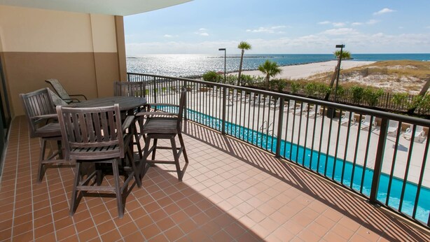 A balcony with a view of the beach and ocean, a pool, and outdoor furniture. - GRAND POINTE 211....LOVELY CONDO, BEST VIEW, CLOSE TO AMENITIES  (Orange Beach)