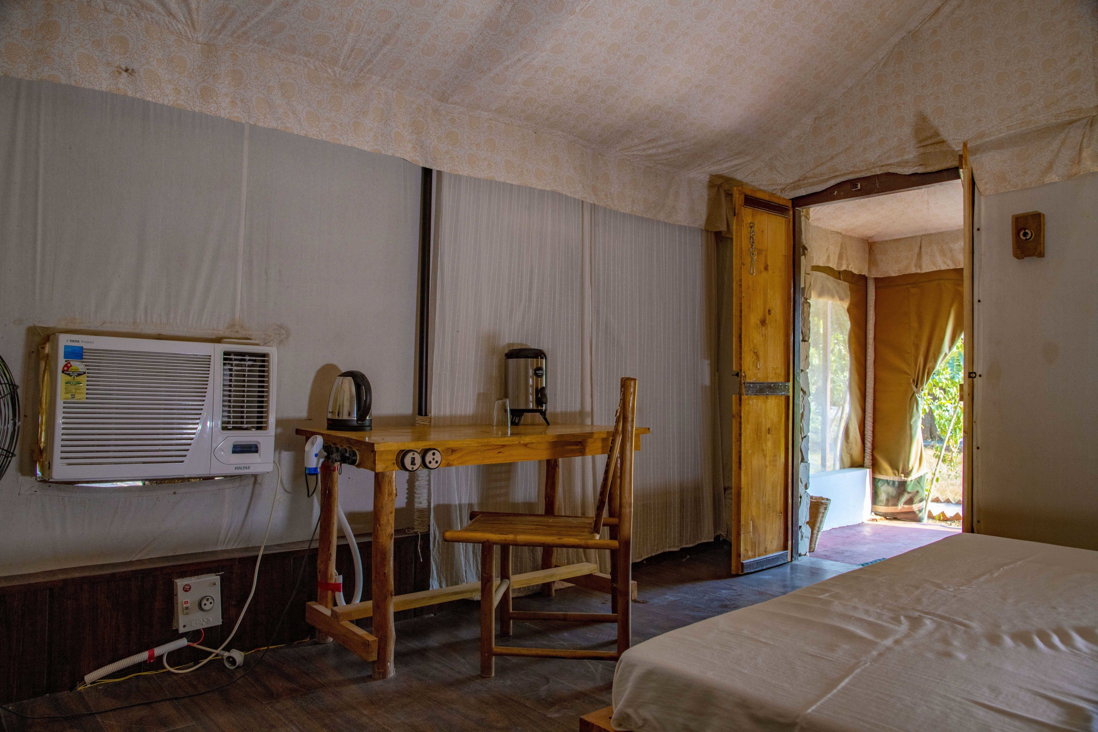 A room with a bed, a wooden desk, an air conditioner, and a door leading outside.