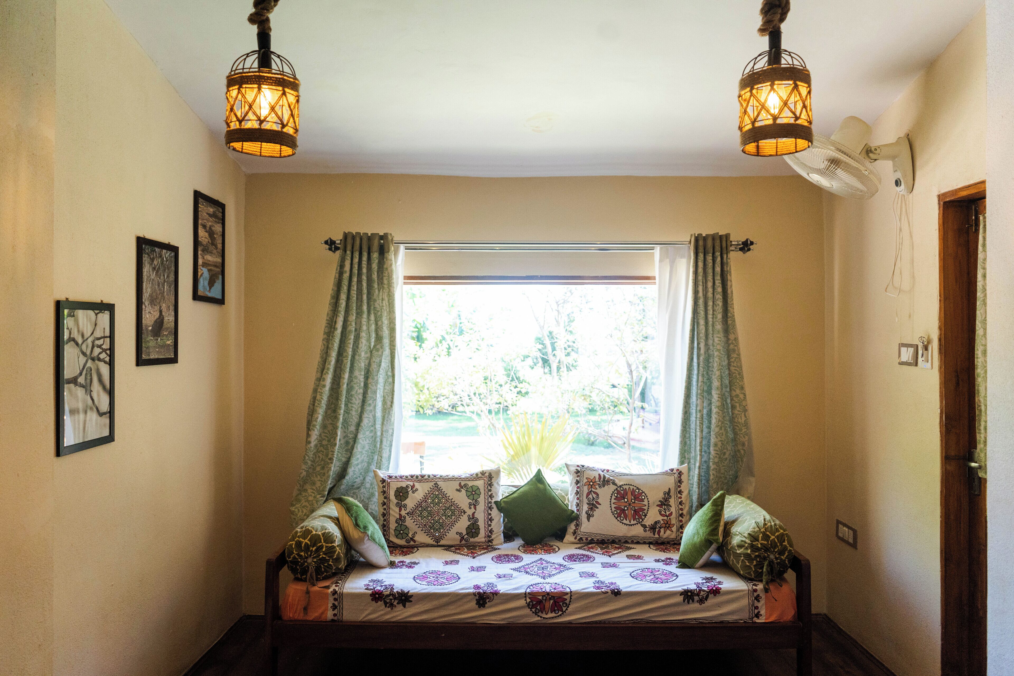 A cozy room with a bed, a window with curtains, and two wall-mounted lamps.