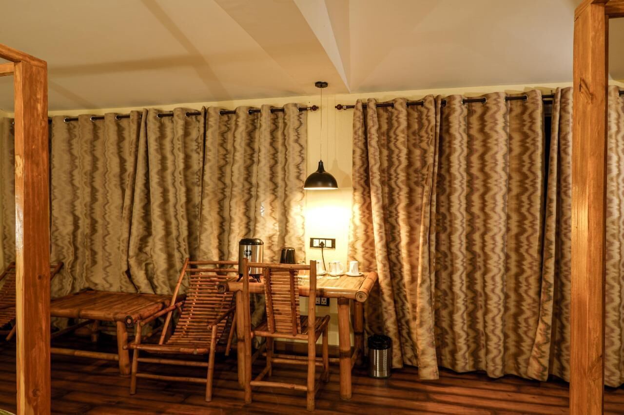 A room with a wooden dining table and chairs, a hanging lamp, and a curtain with a wavy pattern.