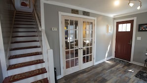 Una escalera de madera con peldaños y un suelo estampado, que conduce a una habitación con una puerta y un ventanal.