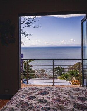 Une chambre avec une grande fenêtre donnant sur une piscine et la mer.