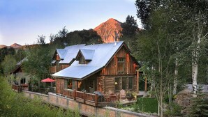 A log cabin with a metal roof, a deck, and a mountain in the background.