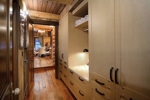 A hallway with wooden flooring, a bench, and a coat rack.