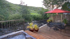 A wooden deck with a hot tub, outdoor furniture, and potted plants.