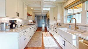 A modern kitchen with white cabinetry, a central island, and a large window.