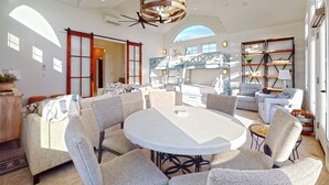 A spacious living area with a round table, multiple sofas, and a large window providing natural light.