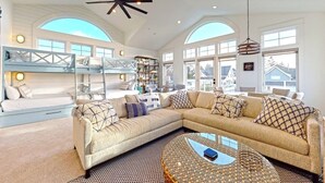 A spacious living room with a large sectional sofa, a coffee table, and a bunk bed area.