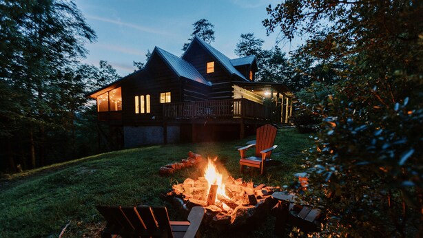 Eine Blockhütte mit Feuerstelle und Sitzgelegenheit im Freien.