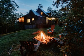 Une cabane en rondins avec un foyer et des sièges d’extérieur.
