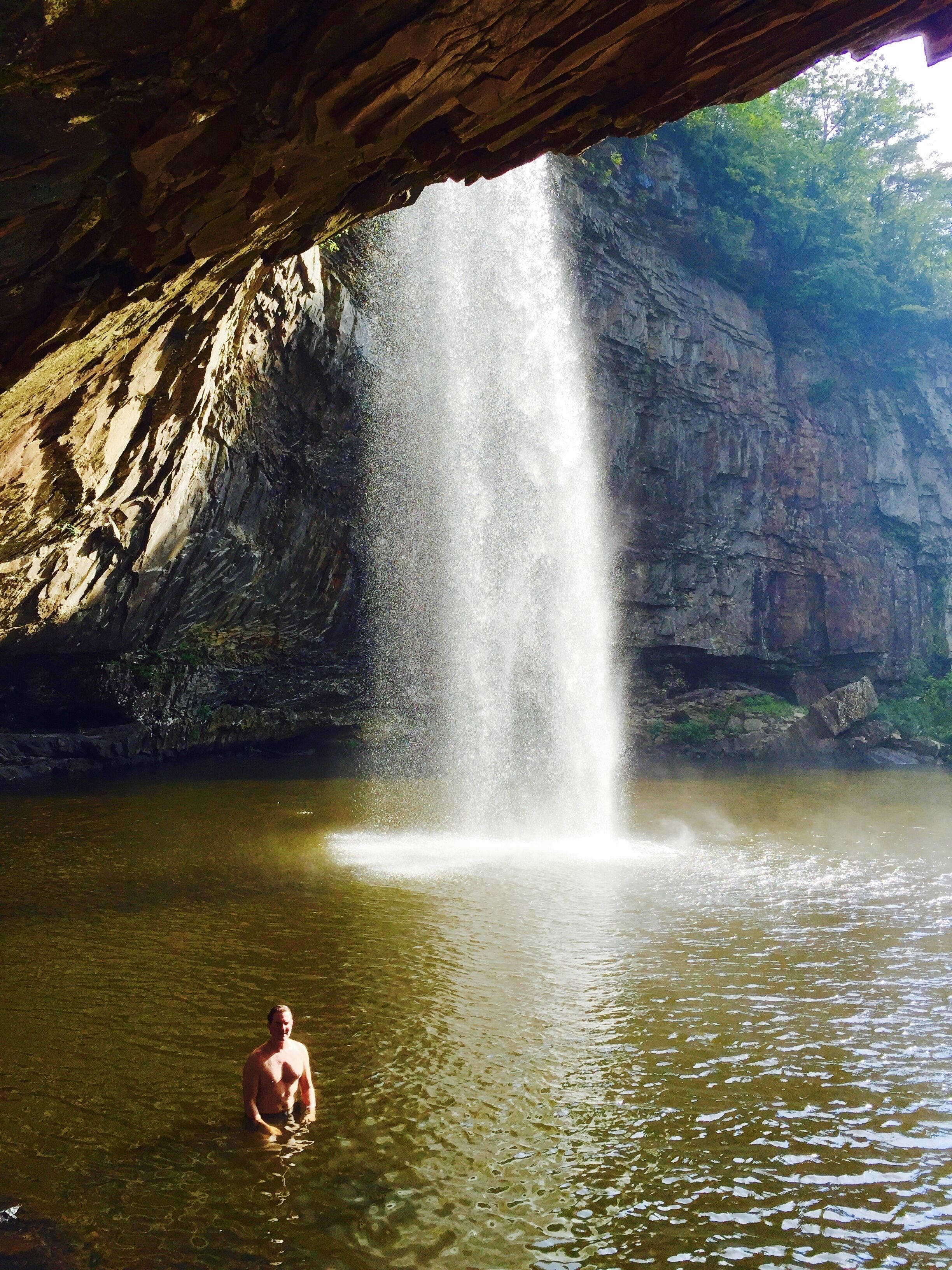 A waterfall in a cave with a person standing in the water.