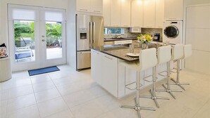 Una cocina moderna con una isla central, electrodomésticos de acero inoxidable y vistas al exterior.