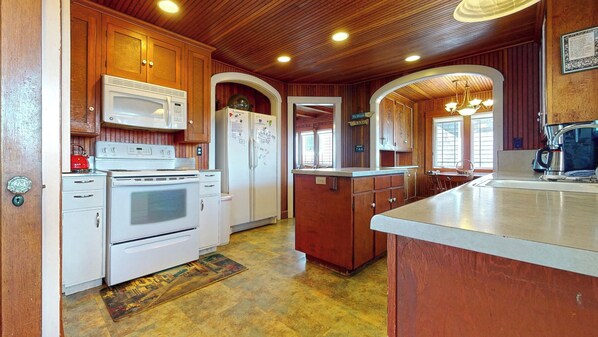 A kitchen with wooden cabinets, a microwave, a stove, and a refrigerator.