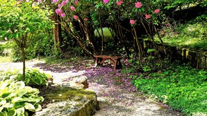 A garden with flowering trees and a wooden bench. - Fayette Springs--Creek House--Enjoy this Spacious Cottage! (Farmington)