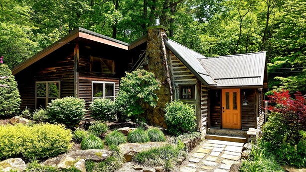 A rustic cabin with a stone chimney, wooden siding, and a stone staircase leading to a wooden door. - Fayette Springs--Creek House--Enjoy this Spacious Cottage! (Farmington)