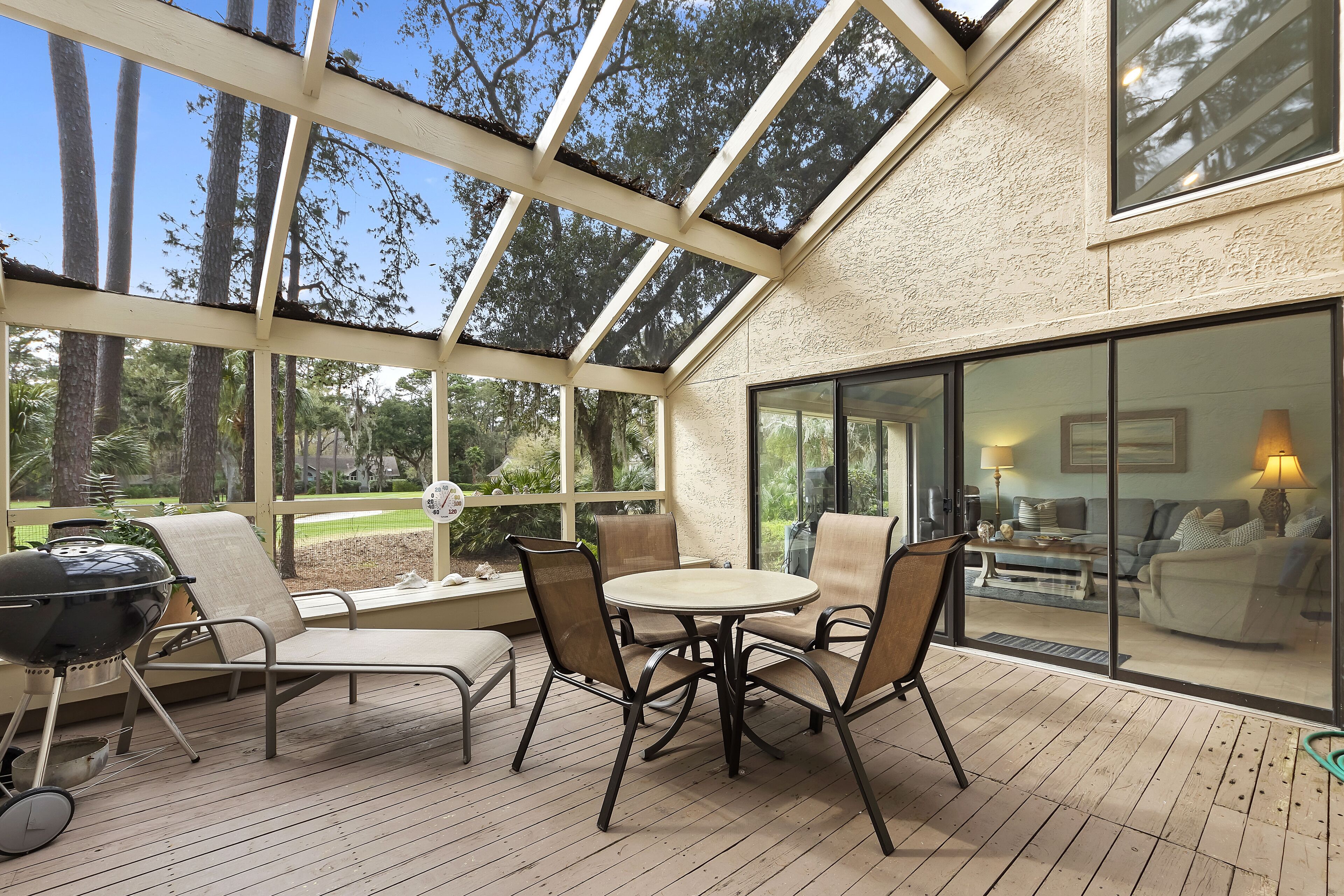 A covered patio with a grill, outdoor seating, and a view of the interior living area.