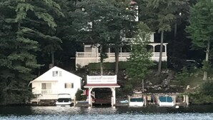 Une propriété au bord du lac, avec une maison blanche, un quai couvert et un bateau.