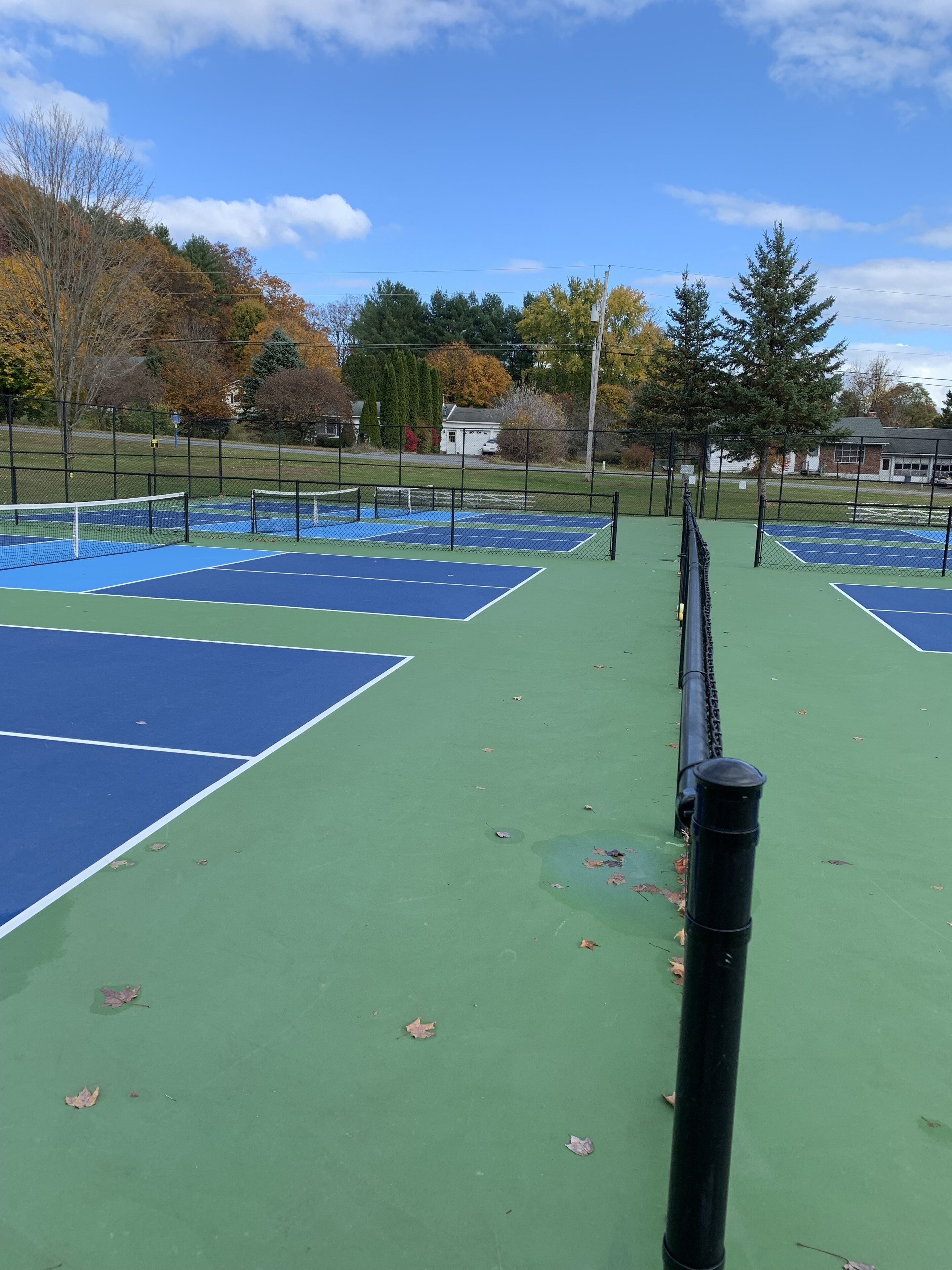 A tennis court with a net in the center, surrounded by a fence.
