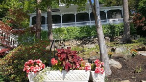 Un jardin avec une clôture blanche, des fleurs rouges et un mur de pierre.