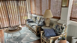 Een gezellige woonkamer met rieten meubels, een gekleurd vloerkleed en een decoratieve lamp.