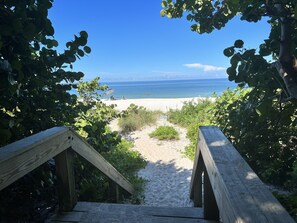 Ein Holzsteg führt zu einem Strand mit freiem Blick auf das Meer.
