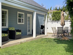 Relax in the backyard with wicker patio furniture, a barbecue grill, and a patio umbrella.