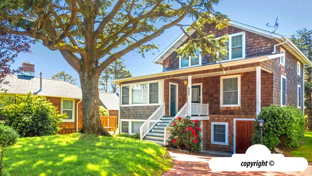 A two-story house with a front porch, a staircase, and a large tree in the yard. - HOT TUB: ESCAPE MANOR: 600ft to BEACH:  Seaside Vacation Homes, Inc Managed  (Seaside)