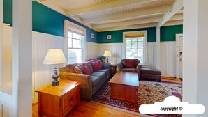 A living room with a sofa, armchairs, a coffee table, and a lamp. There are windows with blinds, a rug, and a door. - HOT TUB: ESCAPE MANOR: 600ft to BEACH:  Seaside Vacation Homes, Inc Managed  (Seaside)