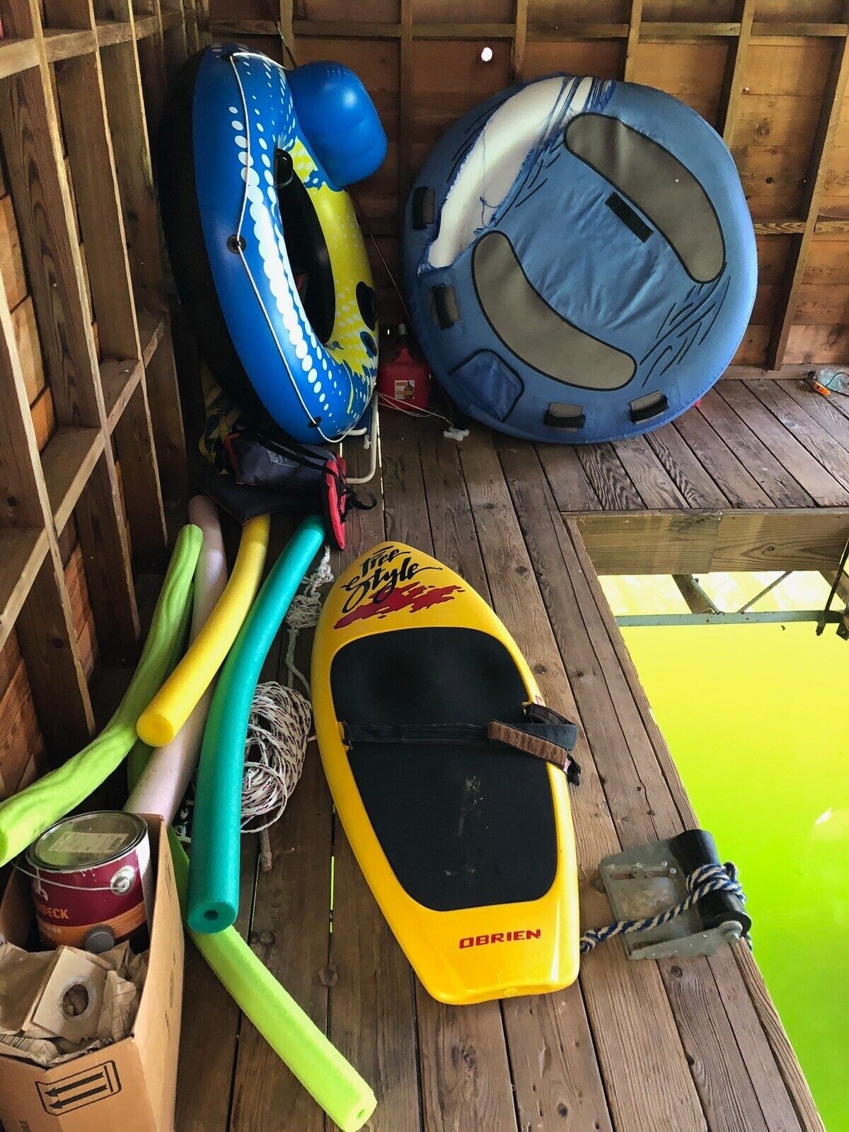 A wooden deck with a kayak, a blue inflatable raft, and a blue inflatable boat.