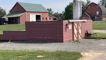 A red barn with a green roof, a silo, and a wooden structure with a sign.